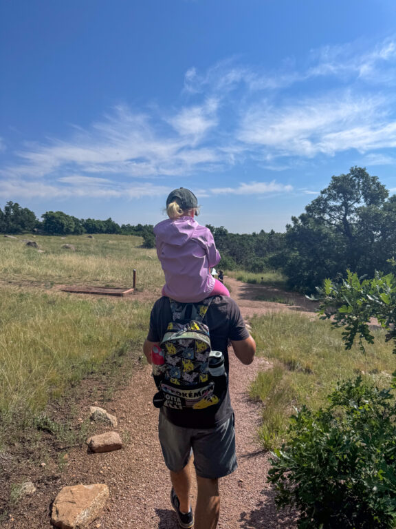 Dad hiking with daughter on shoulders hiking with kids