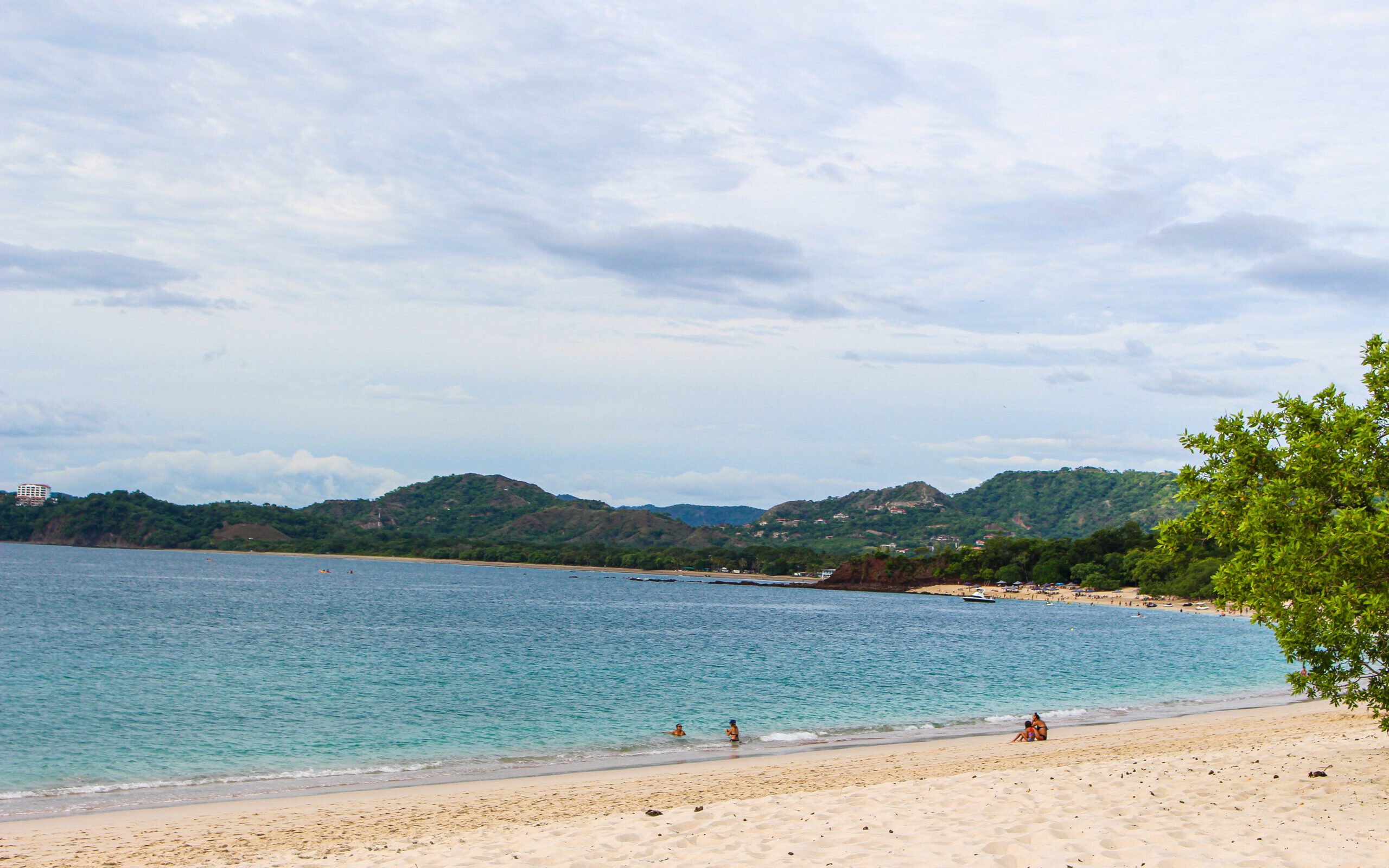 Family enjoying Playa Conchal beach on a Costa Rica trip with turquoise water and lush green hills