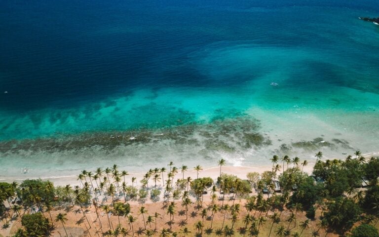 Aerial view of Senggigi Beach in Lombok Indonesia with palm trees white sand and turquoise water over a coral reef