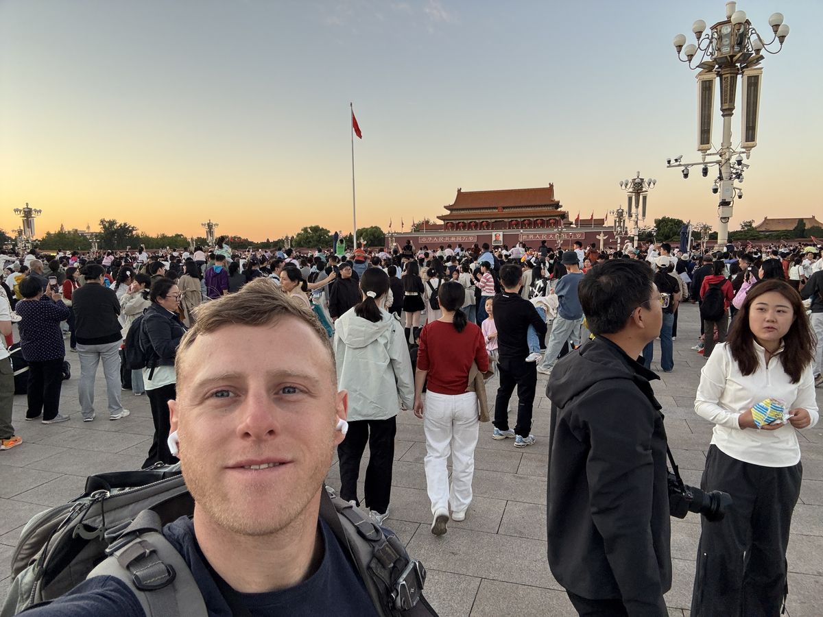 Jambosim Review: Is This Cheap Esim Worth It? (Honest Test) Olly gaspar taking a selfie in a crowded tiananmen square at sunset with tiananmen gate behind him