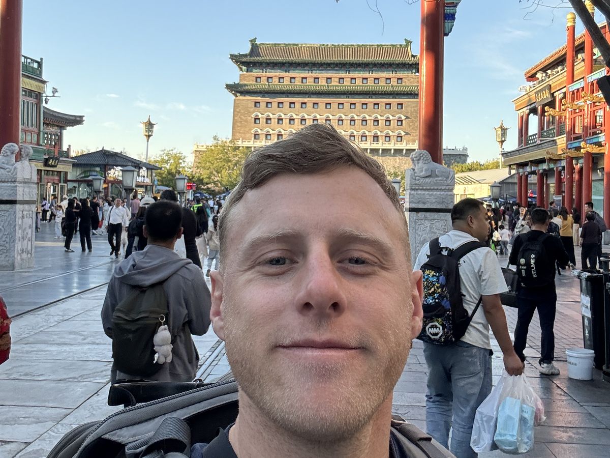 Jambosim Review: Is This Cheap Esim Worth It? (Honest Test) Olly gaspar taking a selfie on qianmen street in beijing with the zhengyangmen arrow tower behind him